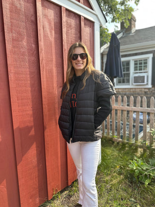Woman wearing a cap sleeve puffer vest in black with jeans