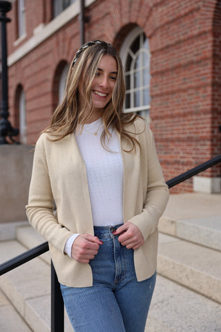 Close-up of a gold knit open front cardigan paired with a white tank and jeans.