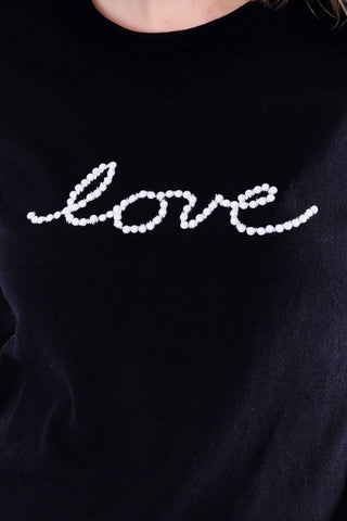 Close up of Black sweater with white embellished pearl love