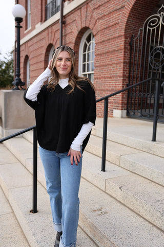 Woman wearing McKenna Capelet in black with modern cable knit design.