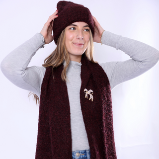 Image 1 (burgundy hat + scarf set with bow brooch): Woman wearing burgundy Poppy Hat and matching scarf with bow brooch, cozy winter knit look.