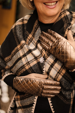 Close-up of metallic bronze Monica Quilted Gloves styled with a plaid wrap – elegant women’s accessories.