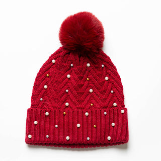 Red knit hat with pom-pom decorated with pearls and gold balls.