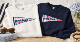 Cabana stripe pennant embroidered with Your Town on a white sweater and navy sweater