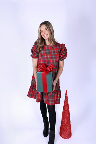 Woman wearing red tartan plaid dress while holding a present