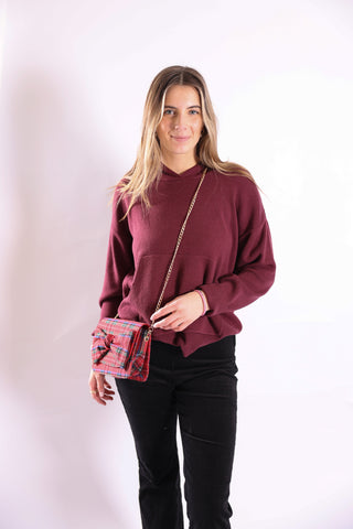 Woman with wearing red tartan cross body bag with gold chain.