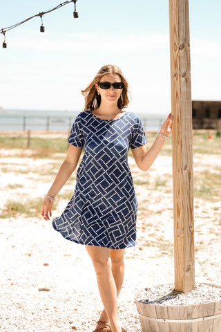 Woman wearing blue and white dress while standing on the beach
