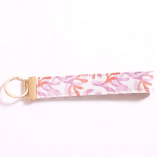 Printed keychain in pink and orange watercolor coral reef pattern.