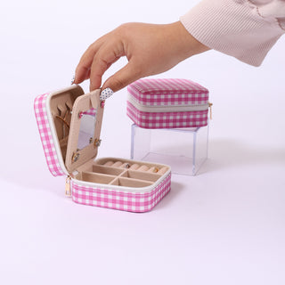 Hand opening a small pink gingham jewelry box with a white background