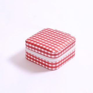 Small square jewelry travel box in maroon gingham pattern with white zipper.