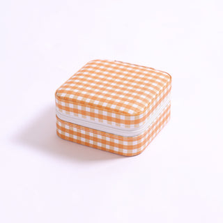 Square gingham print travel jewelry case in bright orange with zipper closure.