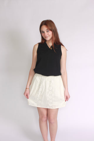 Woman wearing a white eyelet skort paired with a ruffle vneck tank top
