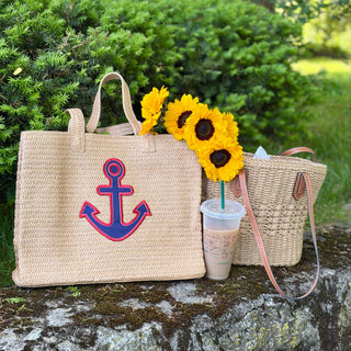 Two straw bags, one navy and red anchor design.