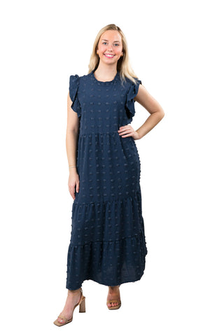 Woman wearing a navy blue dress with white polka dots on a white background
