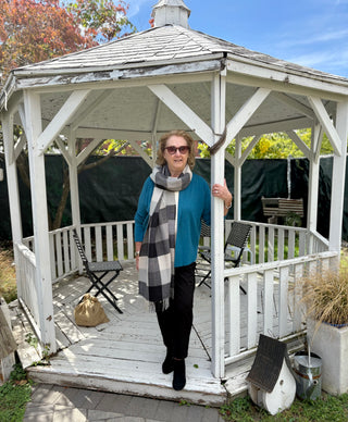 Woman standing in front of a white gazebo with a checkered scarf