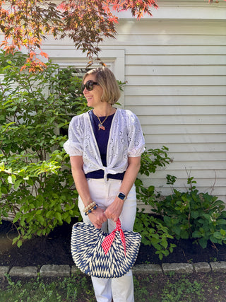 Woman holding a blue and white patterned handbag accented with red and white gingham twillie