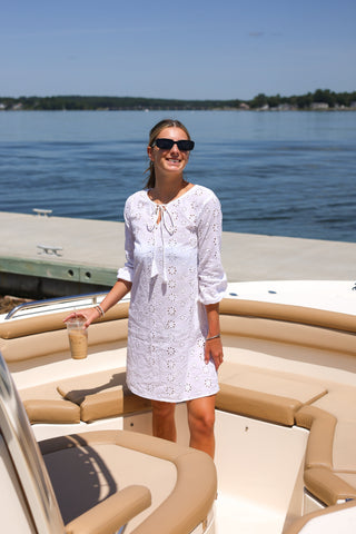 Woman wearing the Shift Style Eyelet Cover-Up in white with tie neckline and 3/4 puff sleeves, standing on a boat dock with iced coffee, perfect beach-to-bar summer look.