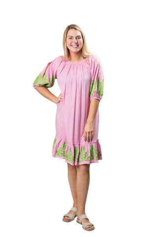 Woman wearing a pink dress with green trim on a white background