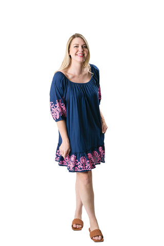 Woman wearing a blue dress with pink floral embroidery on a white background