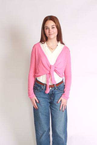 Woman wearing a pink tie front cardigan paired with jeans