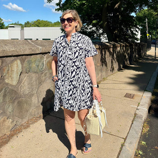 Woman in a navy and white printed  dress standing on a sidewalk