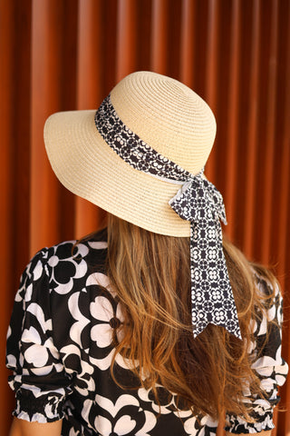 Woman wearing Brigitte Twillie Ribbon Hat with black and white floral ribbon bow, styled for summer.