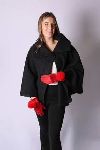 Woman wearing black Kristen Cape with black knit hat and red gloves
