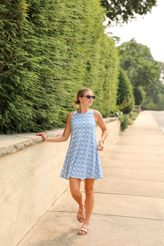 Woman wearing sleeveless A-line dress with pockets in blue and white floral lace print