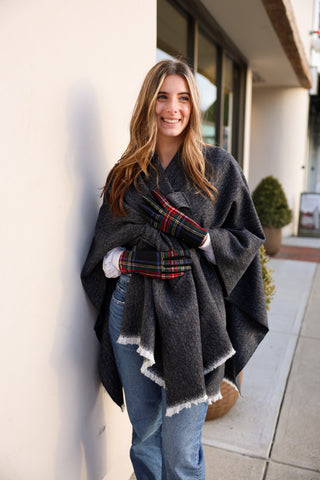 Woman outside in black oversized cozy wrap styled with plaid gloves and jeans.