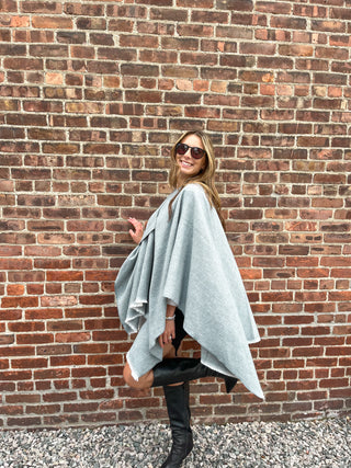 Woman modeling igray oversized cozy wrap styled over black top and jeans.