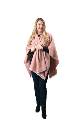 Woman modeling light pink oversized cozy wrap styled over black top and jeans.