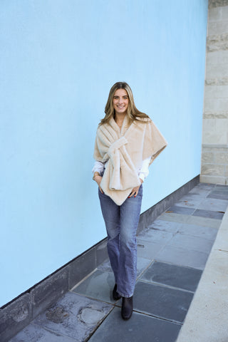 Model wearing the Katie Faux Fur Wrap in beige with diamond-point back and keyhole closure.