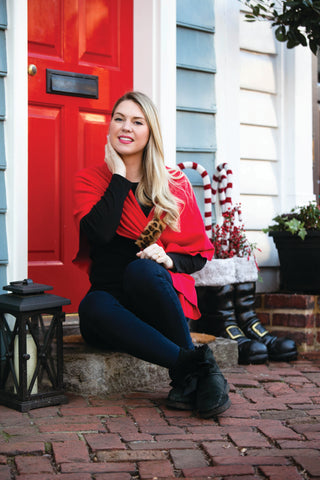 Woman sitting on a step in front of a red door with candy cane decorations.
