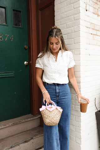 Woman wearing blue jeans and a white top while holding a bag