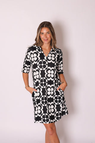 Woman wearing the Sage Dress in bold black and white floral print, featuring a classic collar and flattering fit.