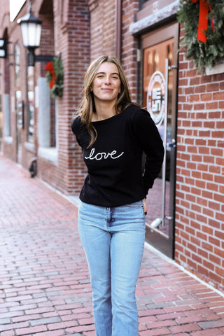 Woman wearing black sweater with the word love written on it