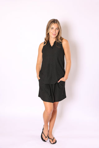 Woman wearing the Goldie Eyelet Top in black, styled with matching black eyelet shorts for a sporty chic look.
