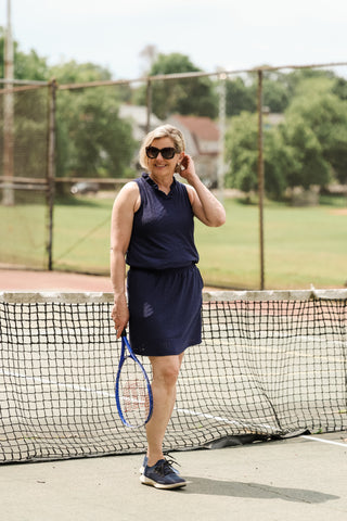 Woman wearing navy pull-on skort with elastic waistband and pockets
