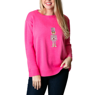 Person wearing a bright pink sweater with a nutcracker design on a white background