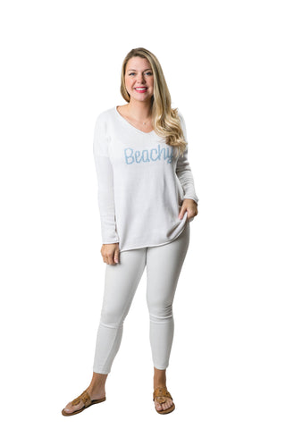 Woman wearing a white sweater with 'Beachy' written in text 
