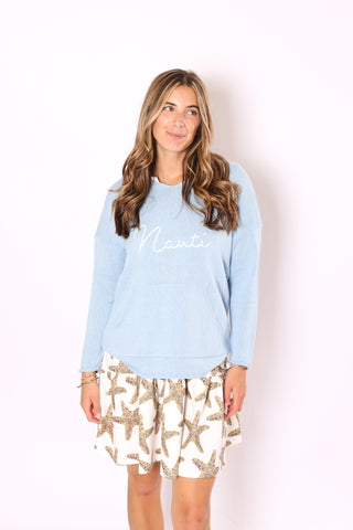 Woman wearing a light blue sweater with "Nauti" embroidered on it