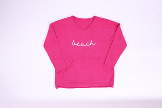 Pink sweater with 'beach' text embroidered on it
