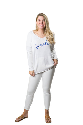 White long sleeve, with long v-neck sweater with blue 'beachy' script on front
