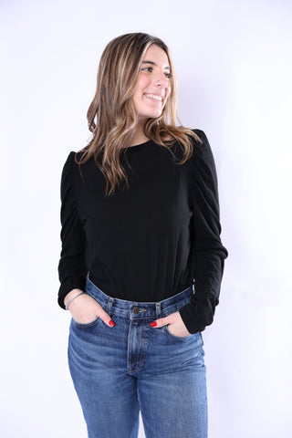 Woman wearing a black top and blue jeans against a white background
