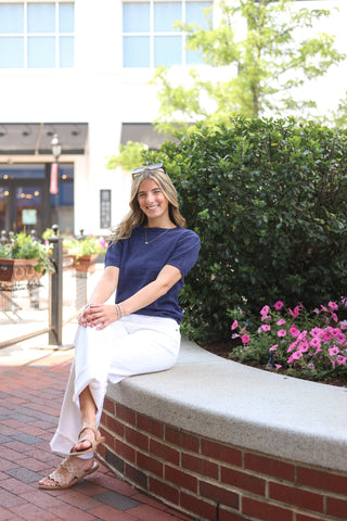 Model wearing the Bea Short Sleeve Sweater in navy, styled casually with white wide-leg pants outdoors.