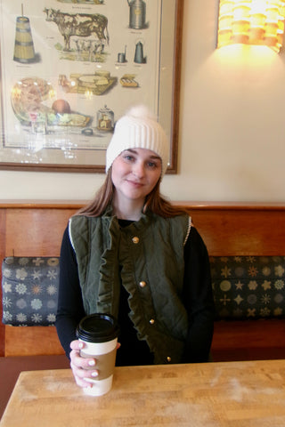 Woman drinking coffee wearing an olive green corduroy vest