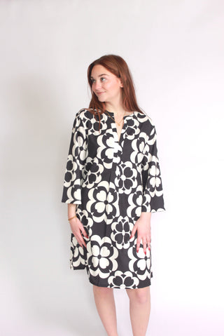Woman wearing a black and white geometric floral patterned bell sleeve dress