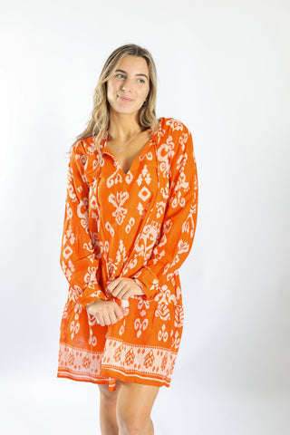 Woman wearing an orange patterned cover-up on a white background