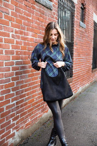 Woman wearing plaid top holding black bag