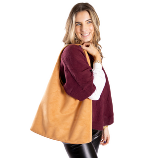 Model is holding camel suede hobo bag